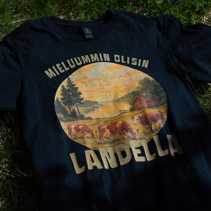 Musta Mieluummin olisin landella -miesten t-paita maalaismaisemaprintillä, aseteltuna sammalelle.