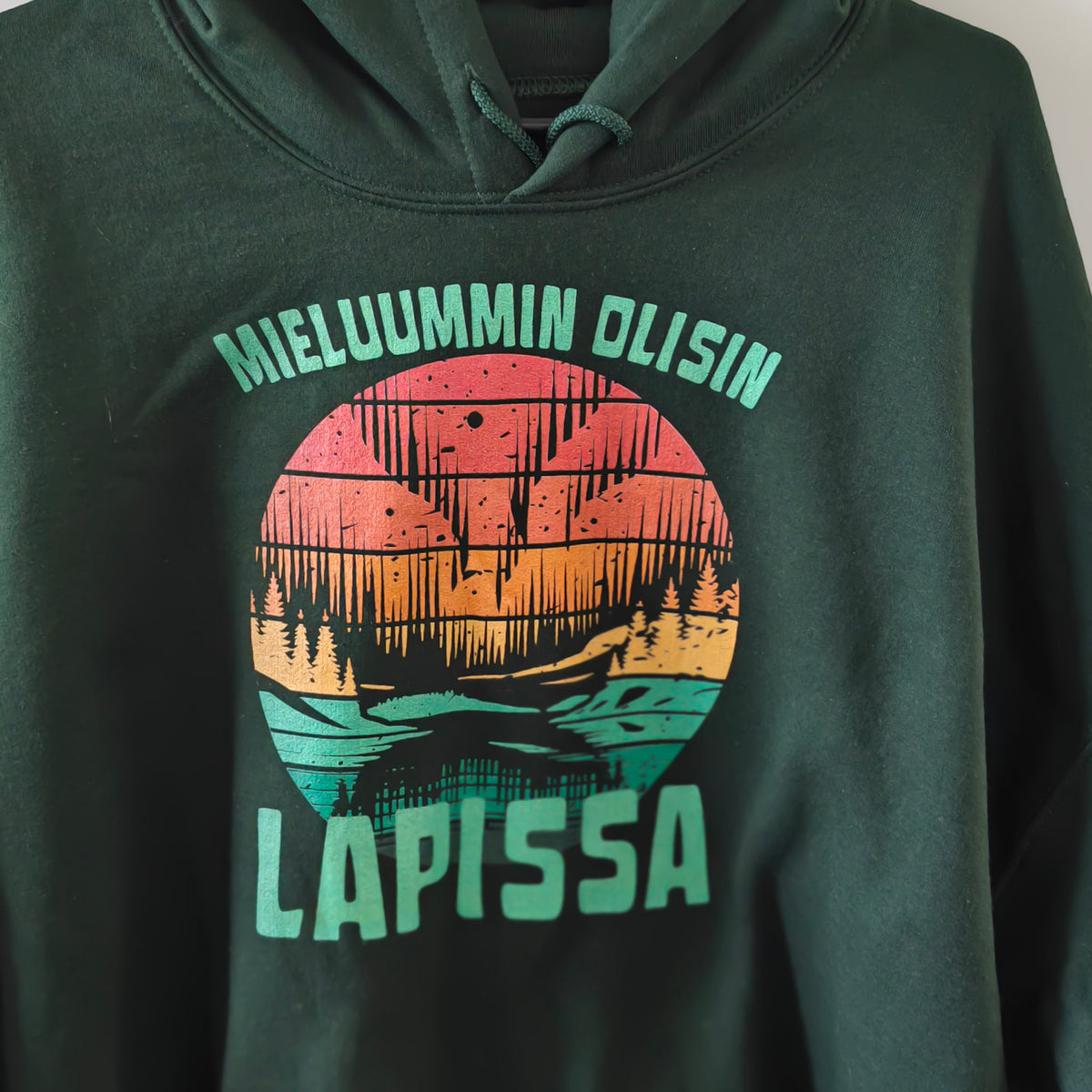 Metsänvihreä Mieluummin olisin Lapissa -huppari pohjoisen maisemaprintillä, lähikuvassa.