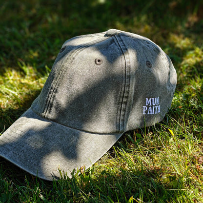 Vihreä Vintage Dad Hat -lippis, jonka sivussa on Mun Paita -kirjailu, kuvattuna viistosti sammalella.